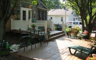 back deck of home with flower pots and chairs